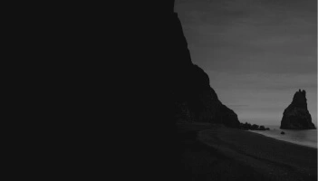 Black and white image of a beach and a cliff