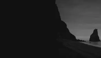 Black and white image of a beach and a cliff