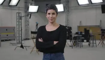 Ashly Burch stood in a studio smiling with arms crossed