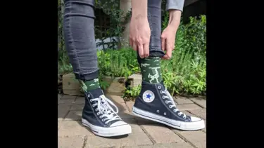 Person in converse pulling up green socks