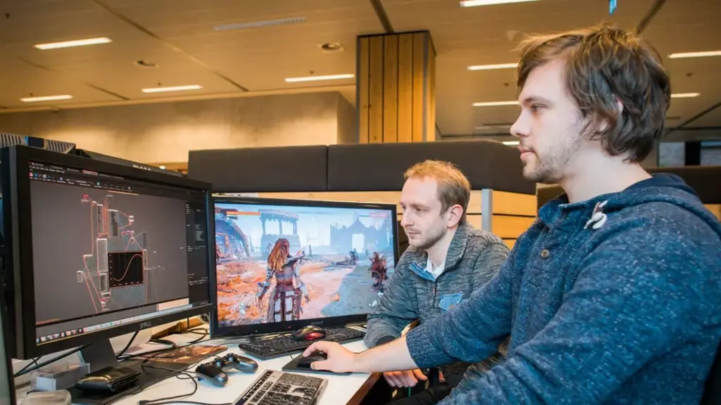Two team members programming at a computer. Computer screen showing Horizon game.